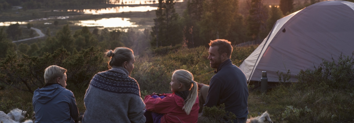 Familie i solnedgang i fjellandskap.